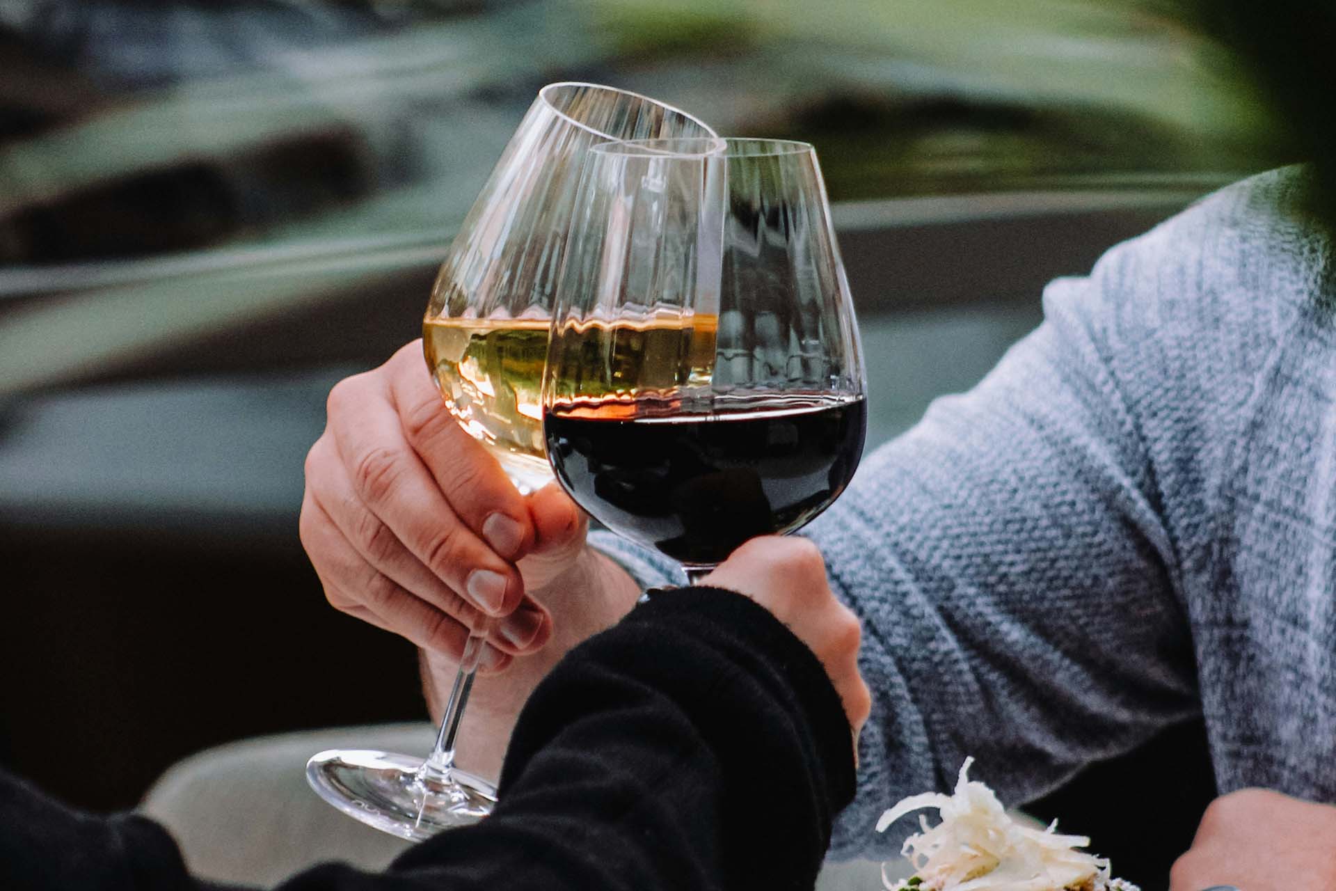 Wine glasses, with red and white wine, raised in a toast