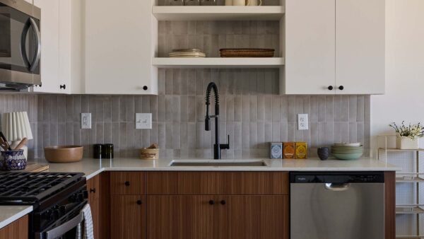 Utah City apartment kitchen with wood style cabinets, light counters, stainless steel appliances, and tiled backsplash.